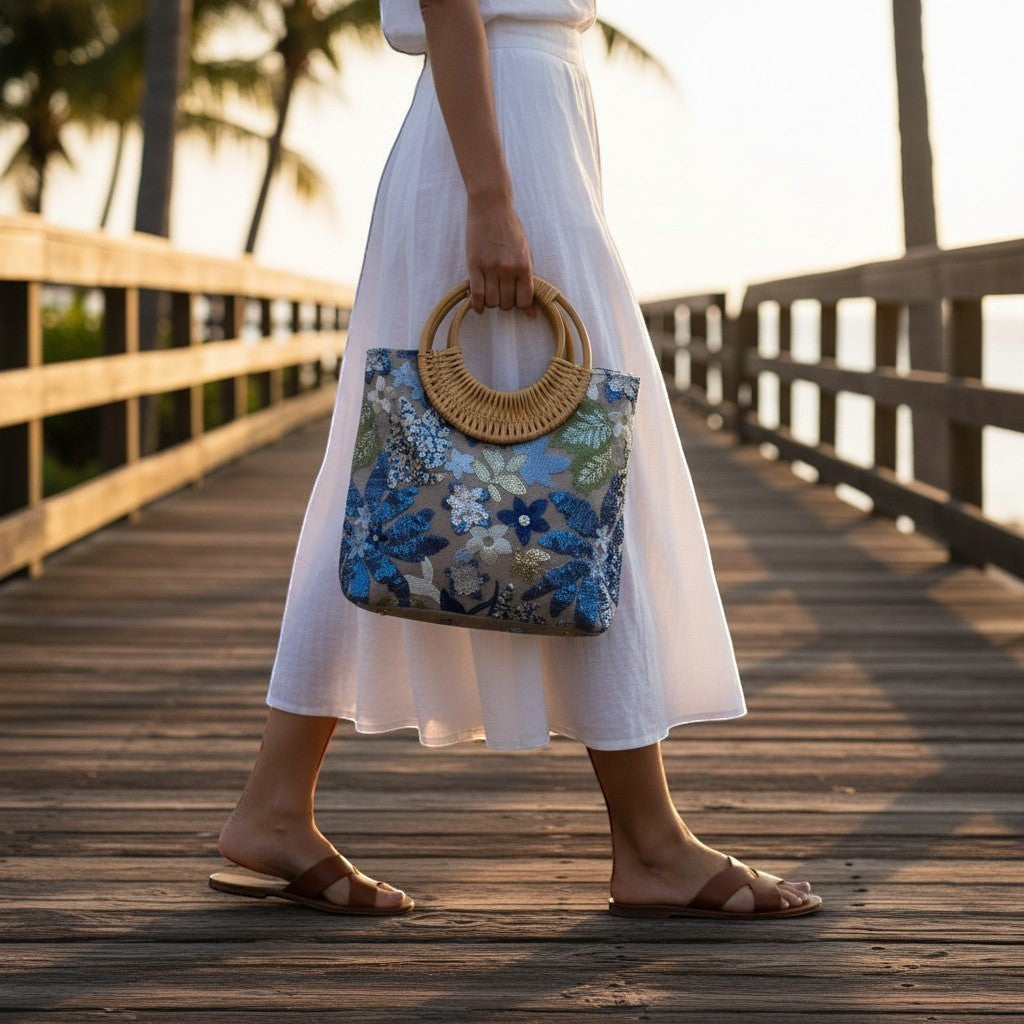 L and B Creations botanical embroidered sequin tote with round bamboo handles, carried on a wooden boardwalk.