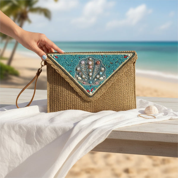 L and B Creations beaded seashell clutch with a straw texture, featuring a turquoise triangular flap on a beach.