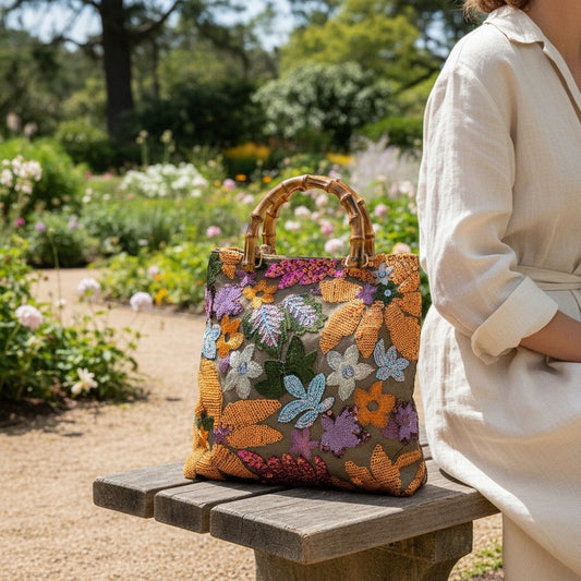 L and B Creations tote handbag with colorful floral sequins and a natural lucite bamboo handle on a garden bench.