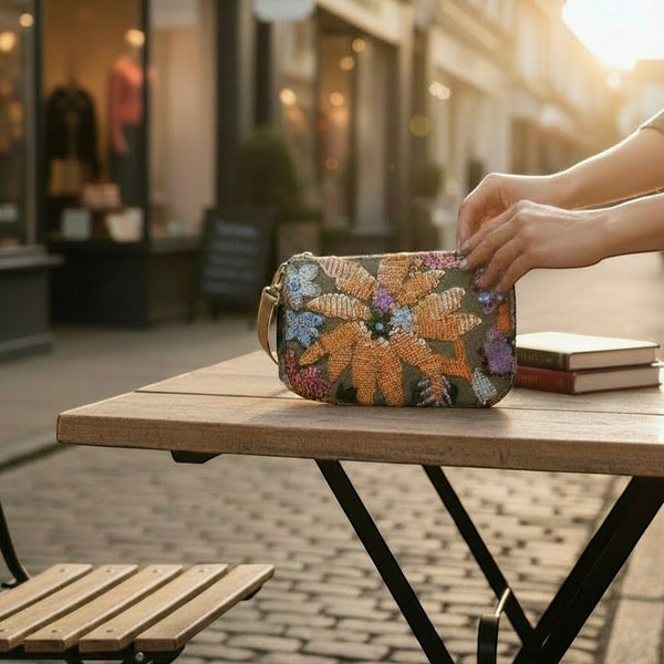 L and B Creations flower sequin purse with removable chain strap, held on an outdoor cafe table.