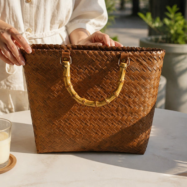 L and B Creations brown woven canvas tote bag with natural bamboo handles held by a person outdoors.